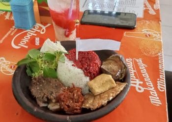 Ria menikmati sajian nasi merah putih yang disajikan warung makan Sambel Pe Simbok di Jalan Penjawi Pati kemarin.